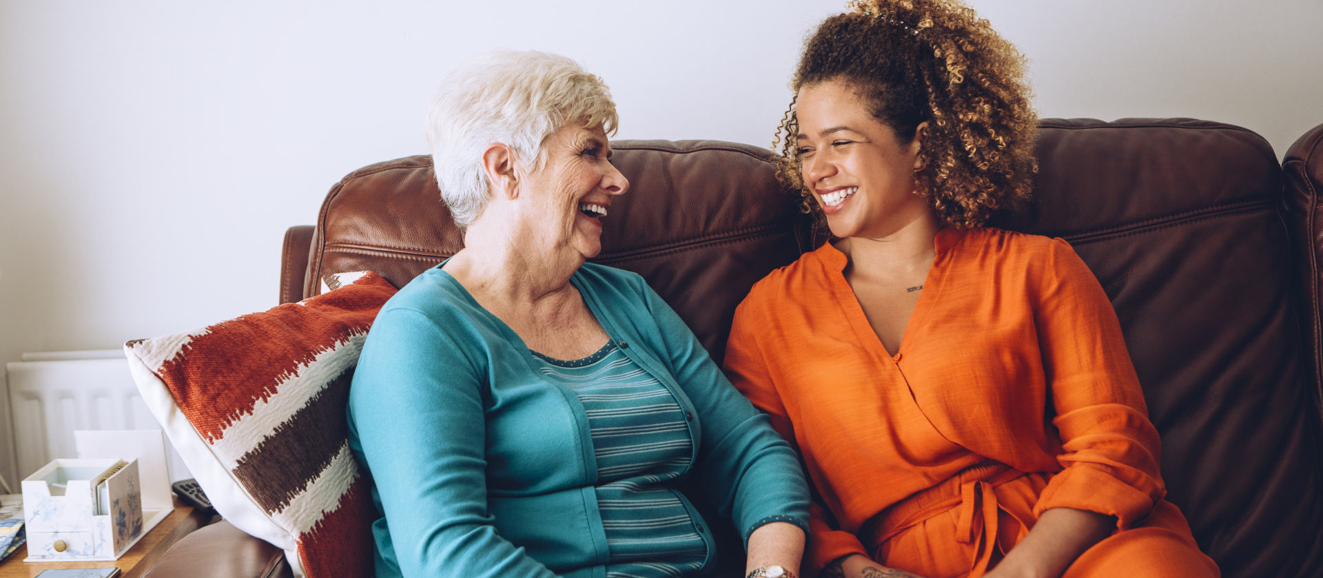  Senior women enjoying a laugh with her granddaughter. They are sitting on the sofa together.